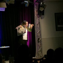 Eine junge Frau auf der Bühne, sie hält ein Bild von einem Panda hoch.